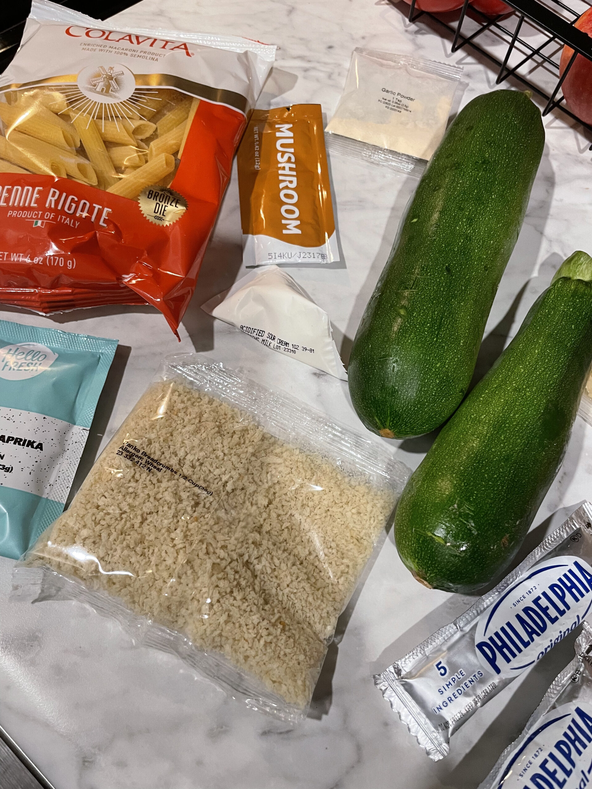 All of the ingredients needed for one of this week's EveryPlate recipes. It includes penne pasta, smoked paprika, mushroom stock concentrate, zucchini, garlic powder cream cheese, sour cream, and parmesan cheese.