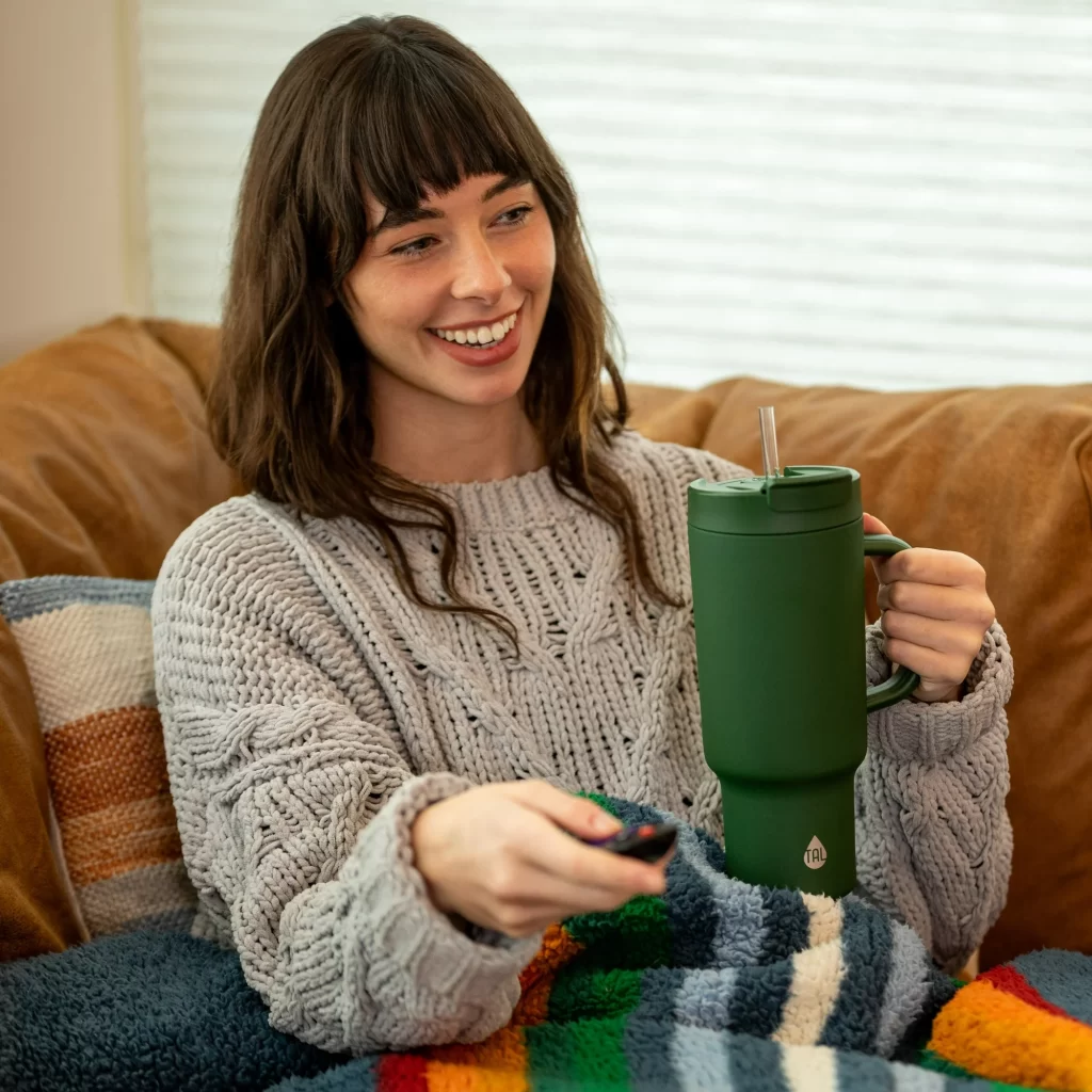 woman holding water tumbler on the couch